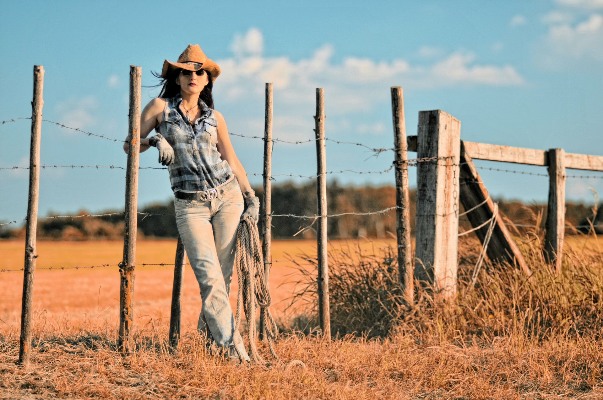 Cowgirl leaning on a fence with a lasso
