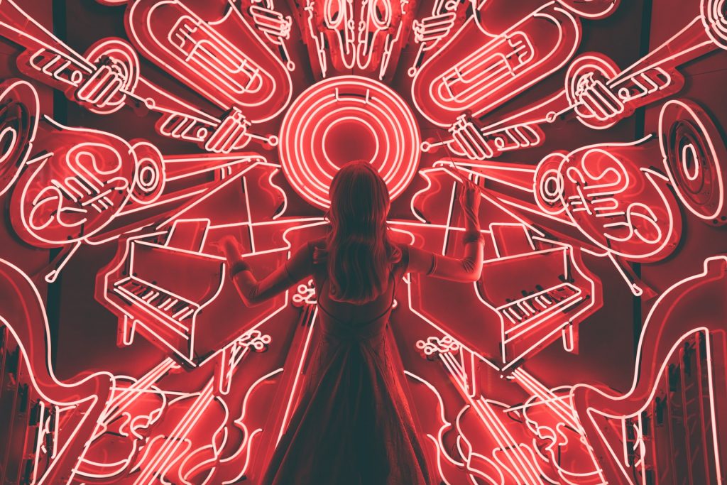 Girl composing music in front of an array of neon instruments