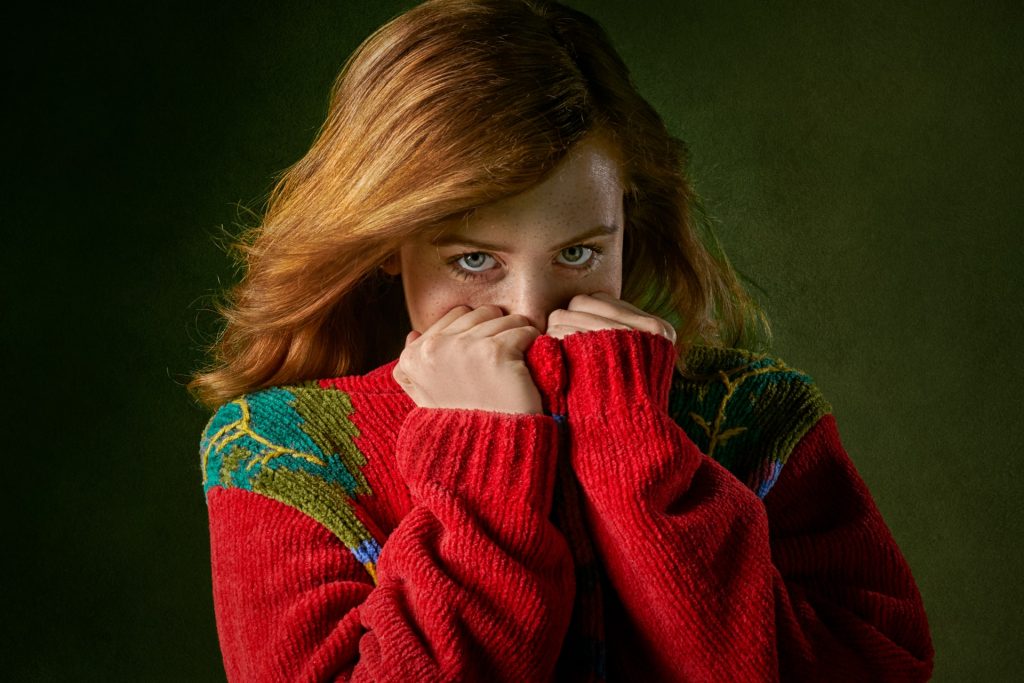 Shy woman in sweater covering her face