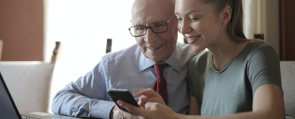 Young Woman Helping an Older Man Sign Up for a Dating Site